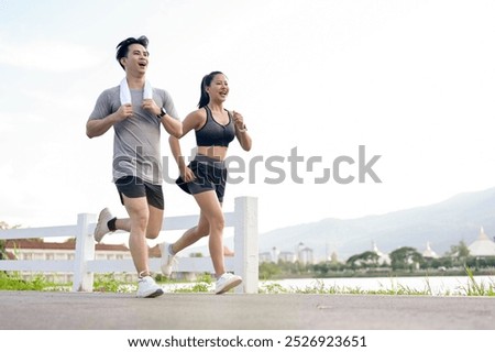 An active, sporty Asian couple in sportswear is jogging or running together in the park in the morning. girlfriend and boyfriend, healthy lifestyle, workout, outdoor activity