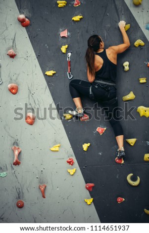 Active sporty woman practicing rock climbing on artificial rock in climbing s. Extreme sports and bouldering concept.