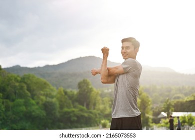 Active and sporty young asian male in sportswear stretching his arms or warming up his body before running in the green park. Sport activities concept - Shutterstock ID 2165073553