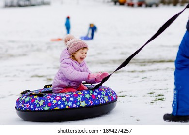 Active Toddler Girl Sliding Down The Hill On Snow Tube. Cute Little Happy Child Having Fun Outdoors In Winter On Sledge . Healthy Excited Kid Tubing Snowy Downhill, Family Winter Time.