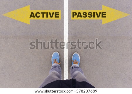 Active vs Passive text on yellow arrows on asphalt ground, feet and shoes on floor, personal perspective footsie concept