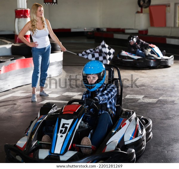 active woman driving sport car for\
karting in sport club, woman with race flag on\
background
