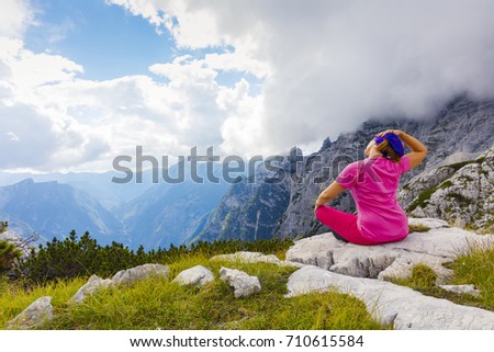 Active woman exercising in the nature above the beautiful valley. Yoga and meditation in the mountains with view. Active lifestyle - healthy lifestyle.