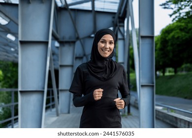 An active woman in hijab running on a city bridge, depicting health, fitness, and an active lifestyle. - Powered by Shutterstock