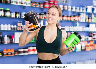 Active Woman Holding Plastic Jar With Sport Nutrition, Reading Label Carefully Before Buying In Shop