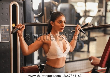 An active woman performs a lat pulldown in the gym, focusing on strength and form.