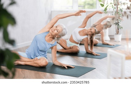 Active women three generations exercising during yoga class in fitness center - vakrasana pose. High quality photo