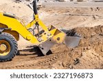 Active work of a powerful pneumatic bucket of a wheeled bulldozer to level an earthen working platform.
