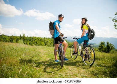 ACTIVE Young couple biking on a forest road in mountain on a spring day