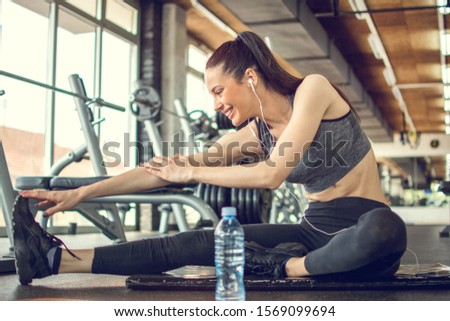 Active young fitness woman stretching at gym