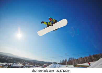 Active Young Man Snowboarding Against Blue Sky