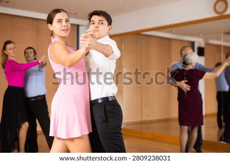 Active young pair practicing ballroom dance in training hall during dancing-classes. Pairs training ballroom dance