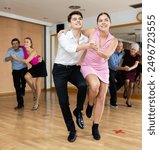 Active young pair practicing Latino dance in training hall during dancing-classes. Pairs training ballroom dance