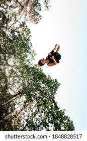 Active Young Pretty Woman With Curly Hair Jumping High And Tumbling In The Air Against The Blue Sky.