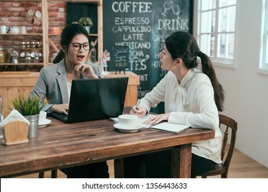 Active Young Smart Confident Businesswoman Helping New Female Worker. Business Freelancer Co Working Space In Cafe Bar Drinking Coffee. Two Asian Office Manager And Employee With Laptop And Notebook