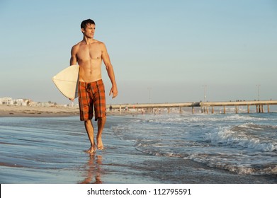 active young surfer holding a surfboard at the beach - Powered by Shutterstock