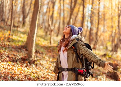 Active Young Woman Carrying Backpack Enjoying Beautiful Autumn Day Outdoors, Mountaineering Through The Forest Path Covered With Colorful Fallen Leaves