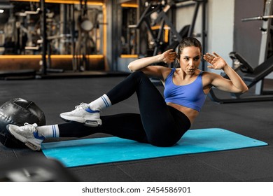 Active young woman doing bicycle crunch sit up exercise on mat, sporty lady in activewear training abs core muscles workout routine in gym - Powered by Shutterstock