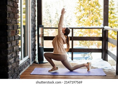 Active young woman doing fitness exercises on yoga mat on open terrace of wooden cottage. Snowy forest on background. Training outdoors during winter time. - Powered by Shutterstock