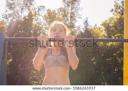 Active and young woman doing pullups.