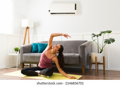 Active Young Woman Doing Yoga At Home During Summer. Beautiful Woman Exercising In The Hot Weather With The Cool Air Conditioner 