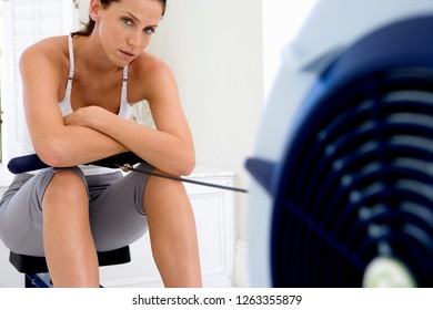 Active Young Woman Exercising At Home On Rowing Machine At Camera