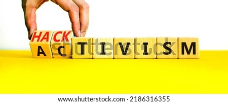 Activism or hacktivism symbol. Businessman turns wooden cubes and changes the word Activism to Hacktivism. Beautiful yellow table white background, copy space. Business activism hacktivism concept.