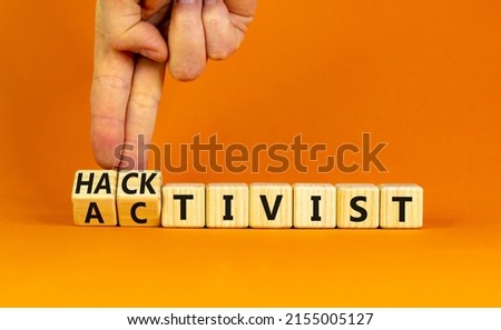 Activist or hacktivist symbol. Businessman turns wooden cubes and changes the word Activist to Hacktivist. Beautiful orange table orange background, copy space. Business activist hacktivist concept.