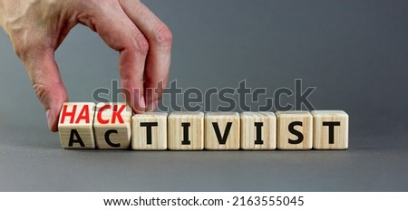 Activist or hacktivist symbol. Businessman turns wooden cubes and changes the word Activist to Hacktivist. Beautiful grey table grey background, copy space. Business activist or hacktivist concept.