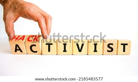 Activist or hacktivist symbol. Businessman turns wooden cubes and changes the word Activist to Hacktivist. Beautiful white table white background, copy space. Business activist or hacktivist concept.