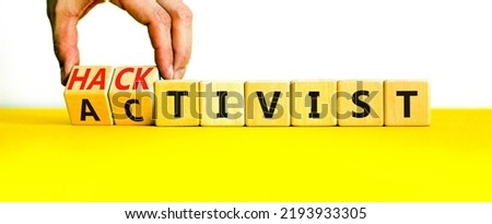 Activist or hacktivist symbol. Businessman turns wooden cubes and changes the word Activist to Hacktivist. Beautiful yellow table white background, copy space. Business activist or hacktivist concept.