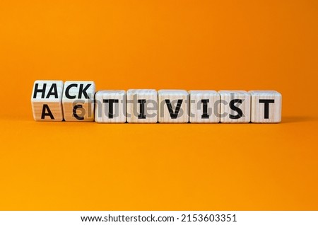Activist or hacktivist symbol. Turned wooden cubes and changed the concept word Activist to Hacktivist. Beautiful orange table orange background, copy space. Business activist or hacktivist concept.