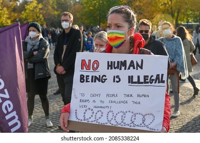 Activist holding board with sign on protest. A woman holding a banner on which it is written "NO human being is illegal". Bundestag in Berlin, Germany. Pro migrants demonstration.
