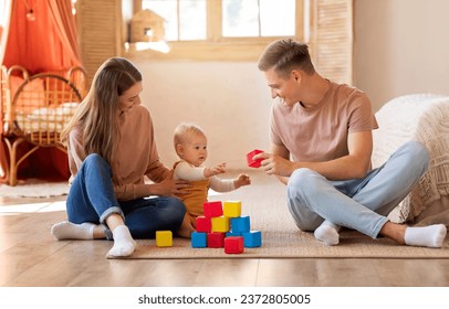 Activities With Babies. Loving Young Parents Playing Building Blocks With Cute Infant Child At Home, Caring Mother And Father Bonding With Their Little Kid, Relaxing In Living Room Together - Powered by Shutterstock