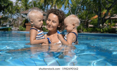 Activities Ideas For Travelling With Kids. Mother Of Twin Girls Spending Time In A Swimming Pool With Them