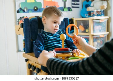 Activities For Kids With Disabilities. Preschool Activities For Children With Special Needs. Boy With With Cerebral Palsy In Special Chair Play With Mom At Home.