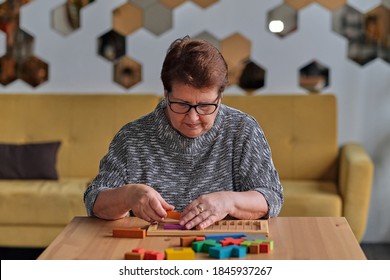 Activity Can Improve Brain Function. Elderly Woman Sitting At Table And Sorting Jigsaw Puzzle Pieces, Free Space Game