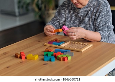 Activity Can Improve Brain Function. Elderly Woman Sitting At Table And Sorting Jigsaw Puzzle Pieces, Free Space Game