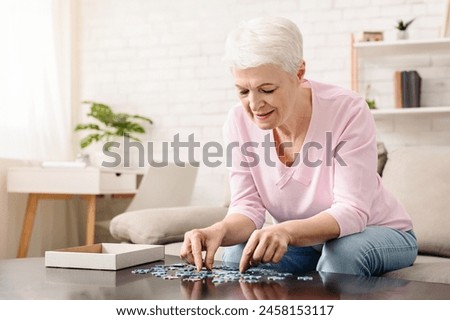 Activity can improve brain function. Elderly woman sitting at table and sorting jigsaw puzzle pieces, free space