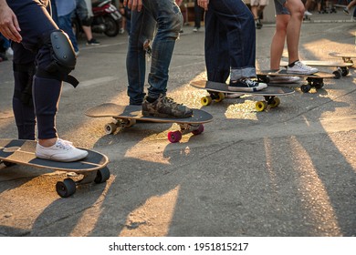 Activity Leisure Skateboard Lifestyle Concept. Legs Group Of Athletic People Playing Surf Skate On The Road With Sunlight In The Evening For Workout.