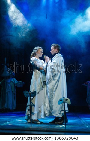 Actor and actress in white costumes play a romantic image on the stage of the theater.