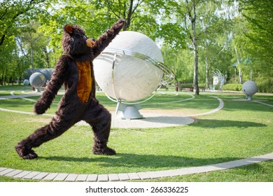actor dressed as bear aerobics near sculptural model of solar system