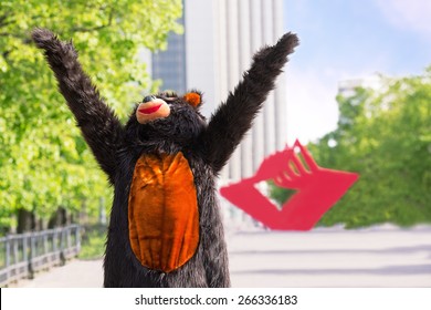 actor dressed as bear enjoys the sun on avenue of park on background of red stars