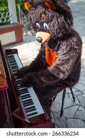 actor dressed as bear plays music on piano on the bandstand in the park