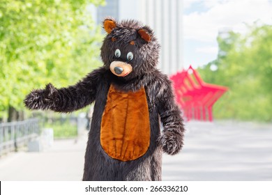 actor dressed as bear walks avenue of park on background of red stars
