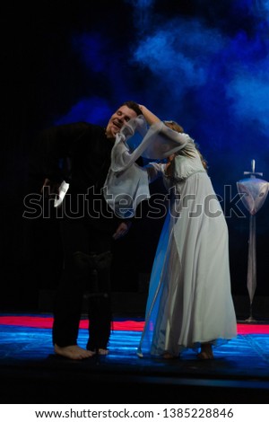 An actor in an old black suit and actress in a white dress on the stage of a theater show a play a drama.