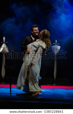 An actor in an old black suit and actress in a white dress on the stage of a theater show a play a drama.