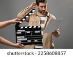 Actor performing while second assistant camera holding clapperboard on grey background, closeup