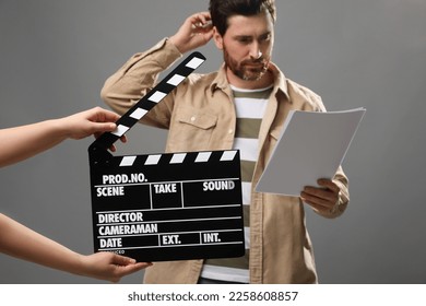 Actor performing while second assistant camera holding clapperboard on grey background, closeup - Powered by Shutterstock