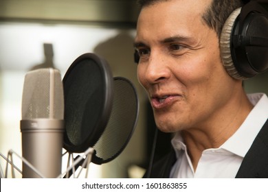actor and radio announcer with headphones and microphone working film dubbing, performing radio spot and singing